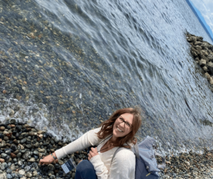 Kristina Fruge by the edge of water bending down to pick up rocks. 